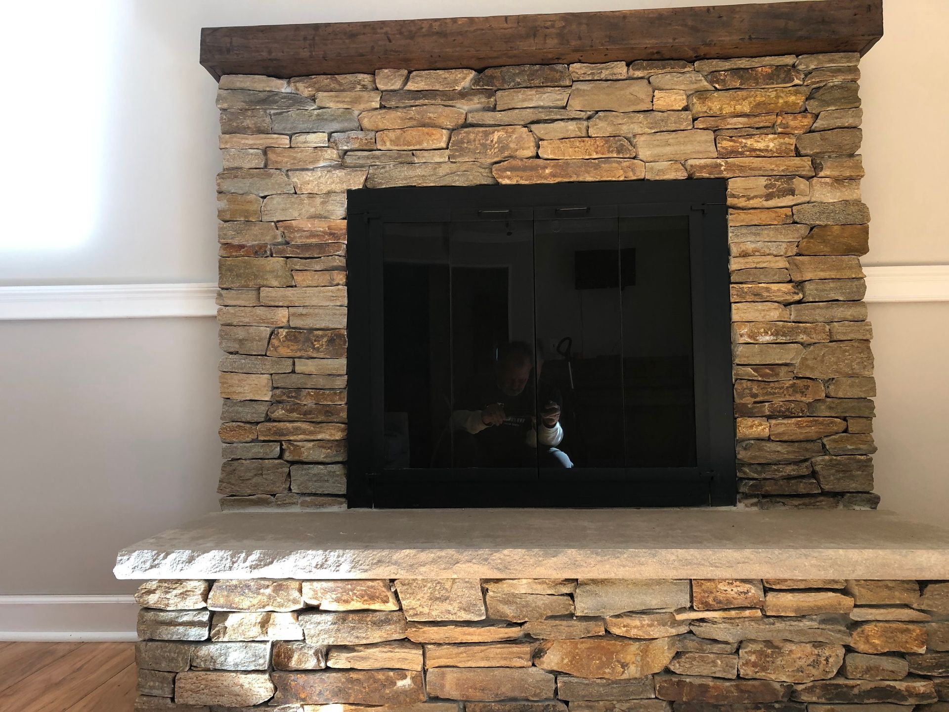 Stone fireplace with a dark glass firebox and a light stone hearth in a room.