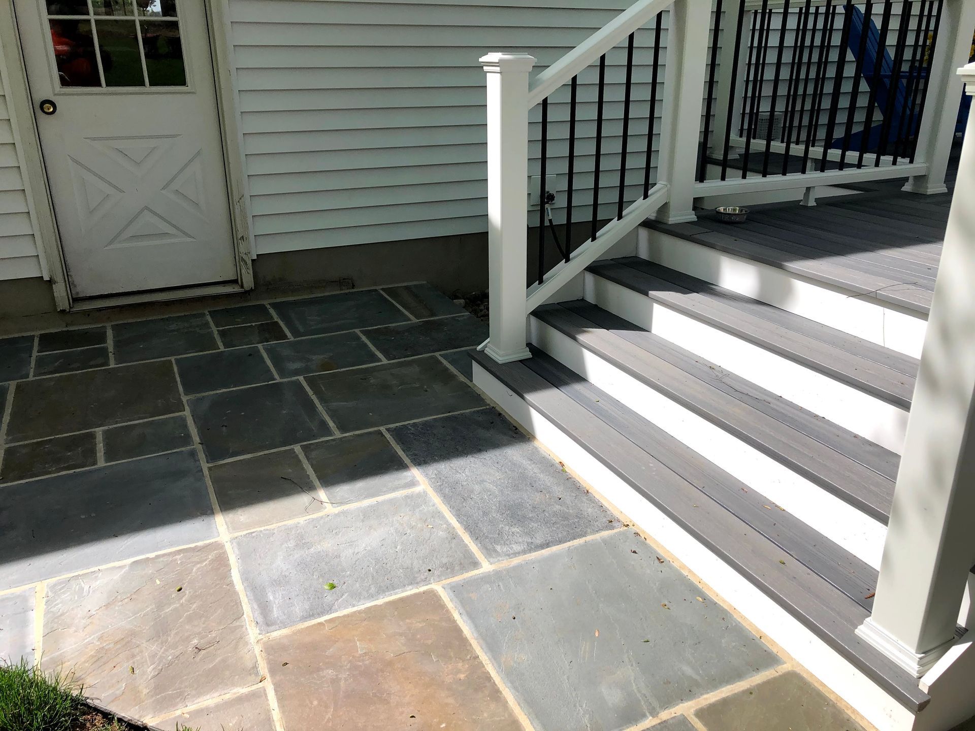 Stone patio beside white stairs and railing leading to a porch door