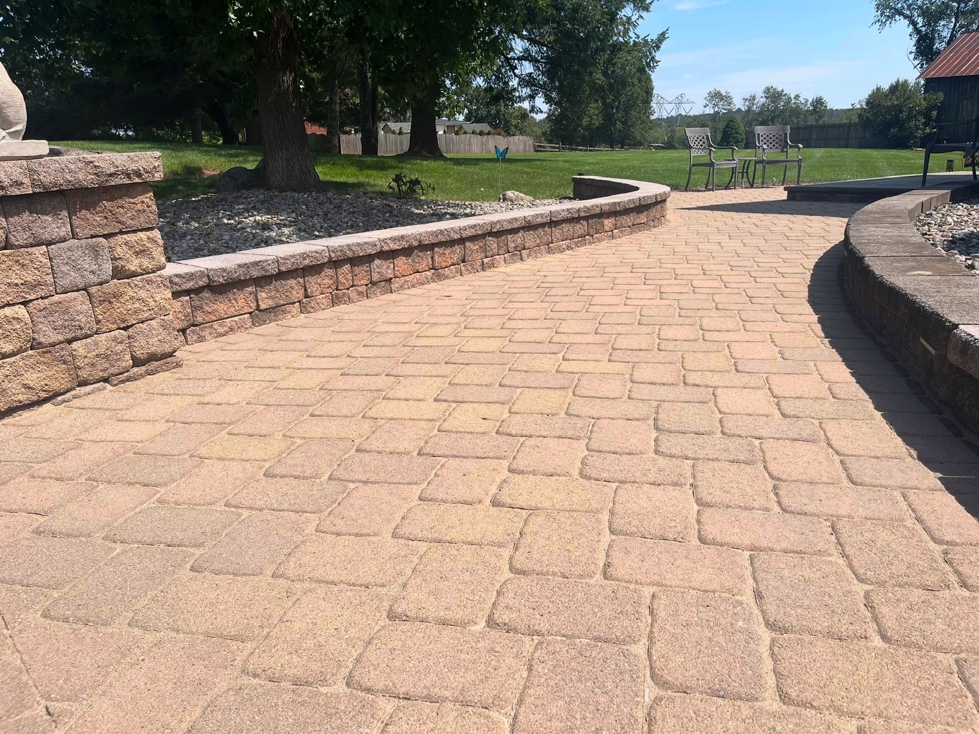 Brick-paved walkway curving through a sunny park with stone edging and trees