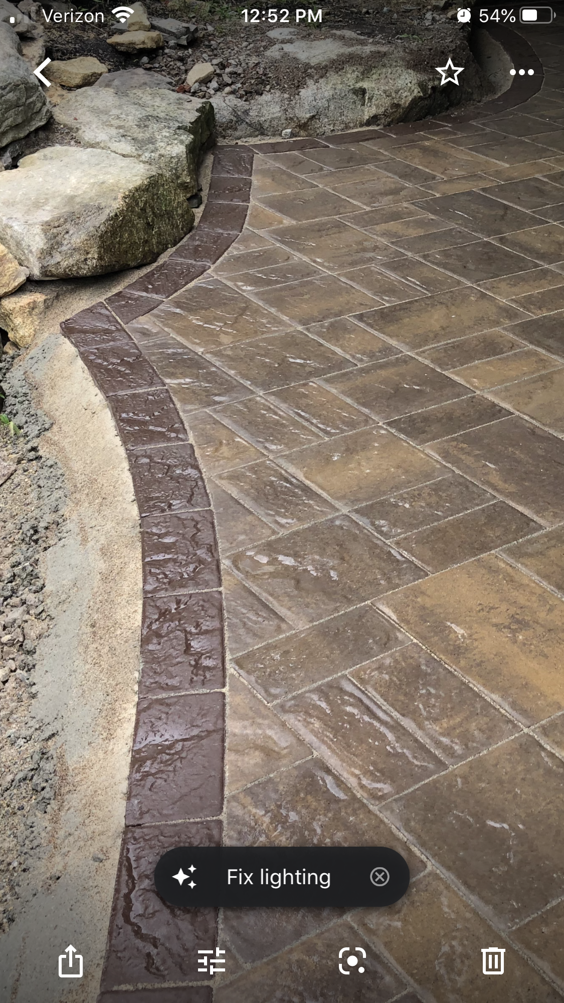Stone garden path curving beside large rocks, bordered with small pebbles and patterned paving stones.