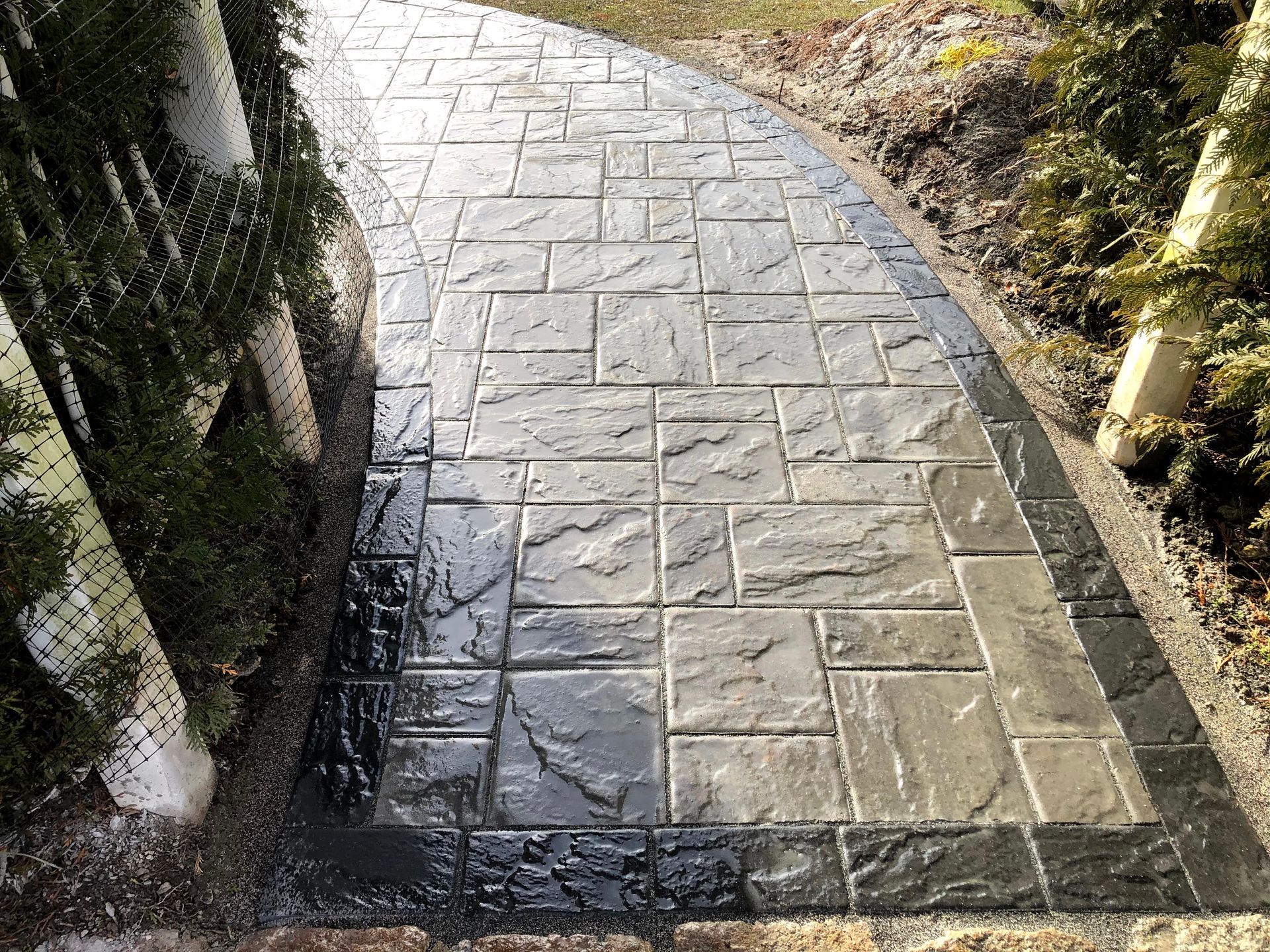 Curved stone walkway bordered by grass and trees, lit by sunlight