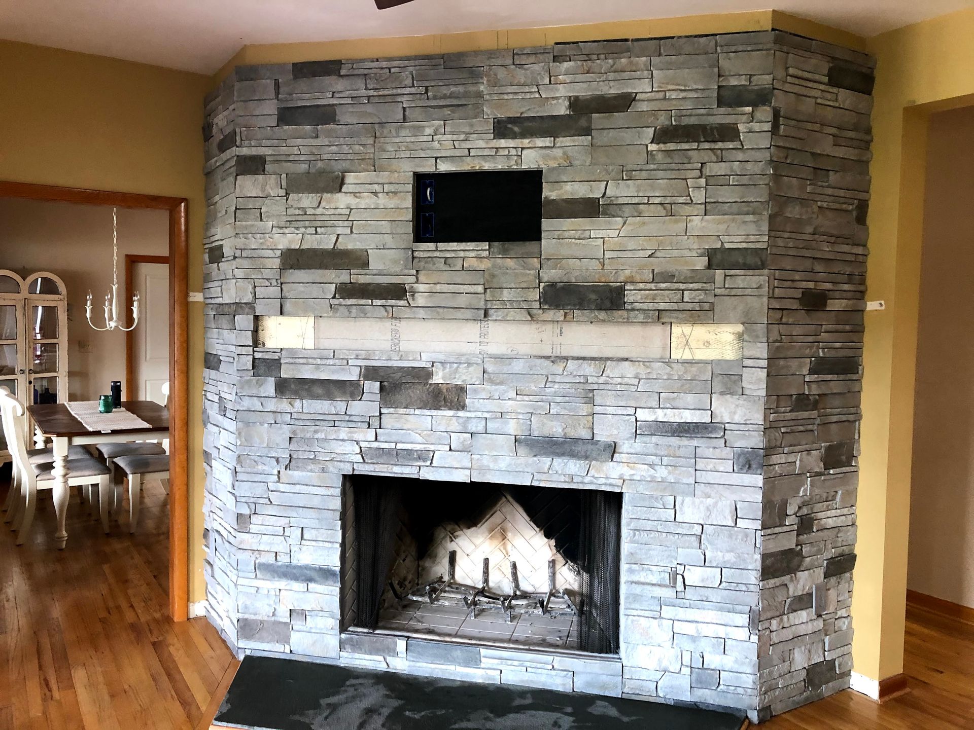 Stone fireplace with a small TV mounted above it in a warm-toned living room.