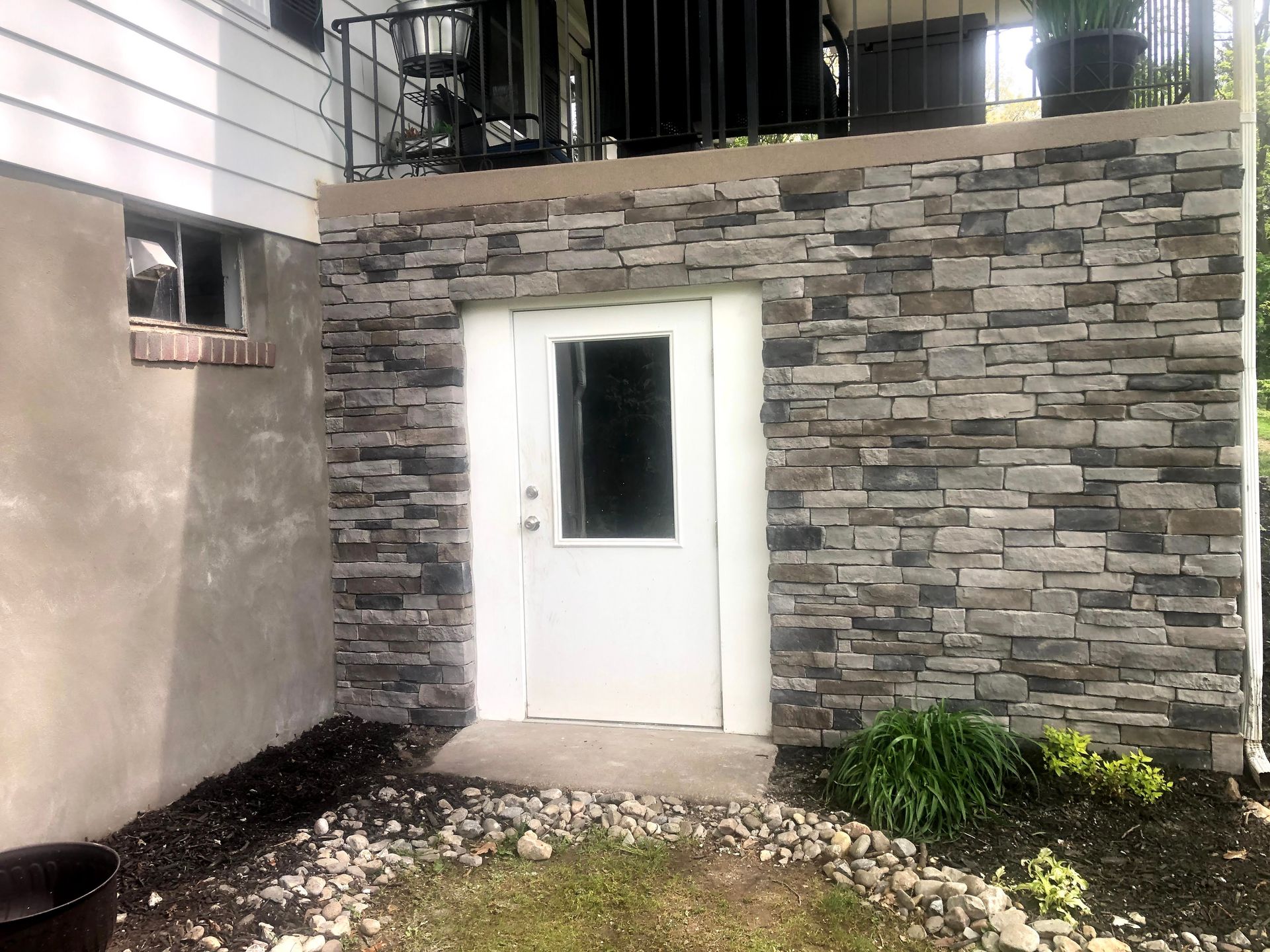 Stone exterior wall with a white door under an upper balcony at night