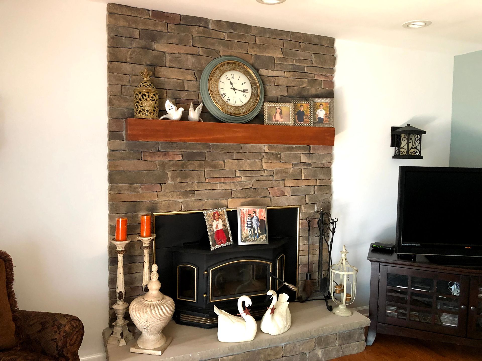 Living room fireplace with brick surround, clock on mantel, and TV on the right