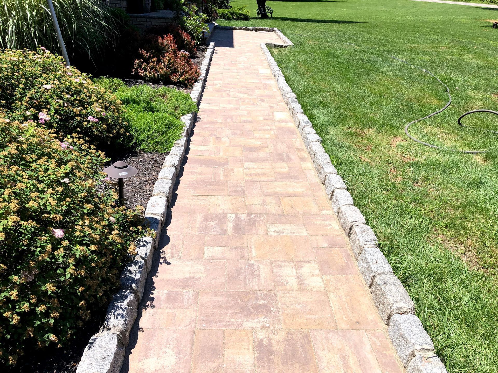 Brick walkway beside a green lawn and garden border