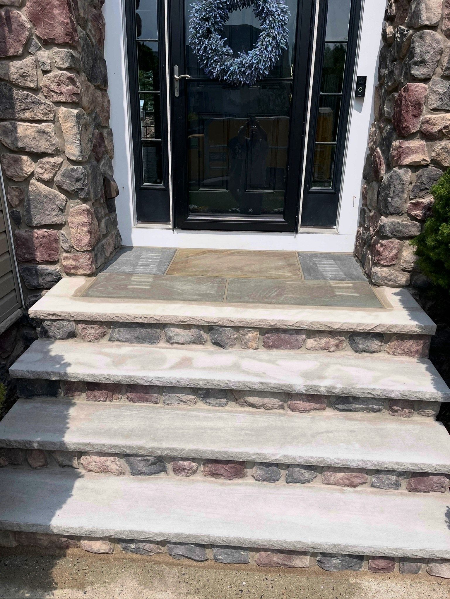 Stone steps leading to a black front door framed by rough stone walls