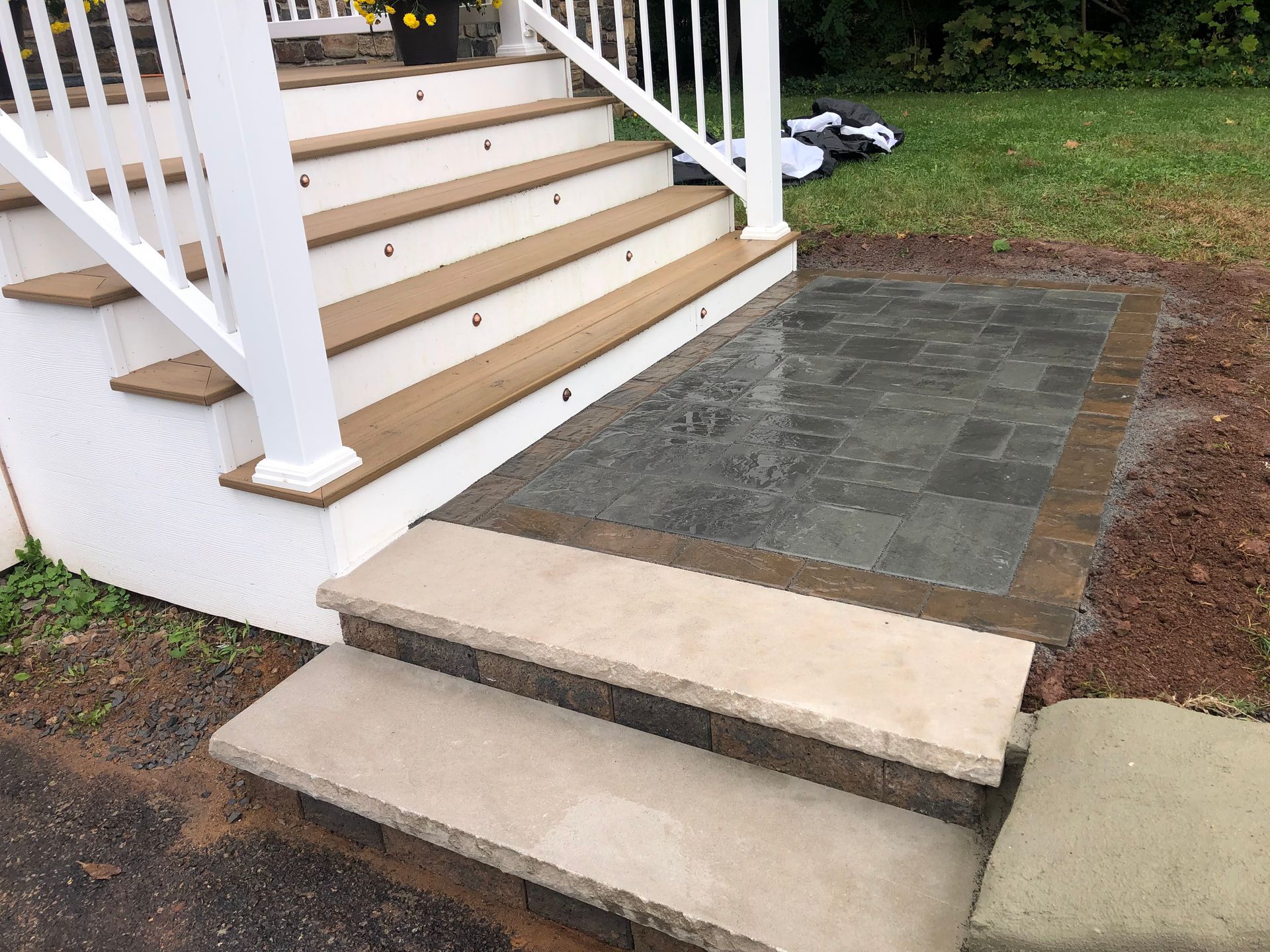 Front steps with white railings leading to a paved walkway and grassy yard