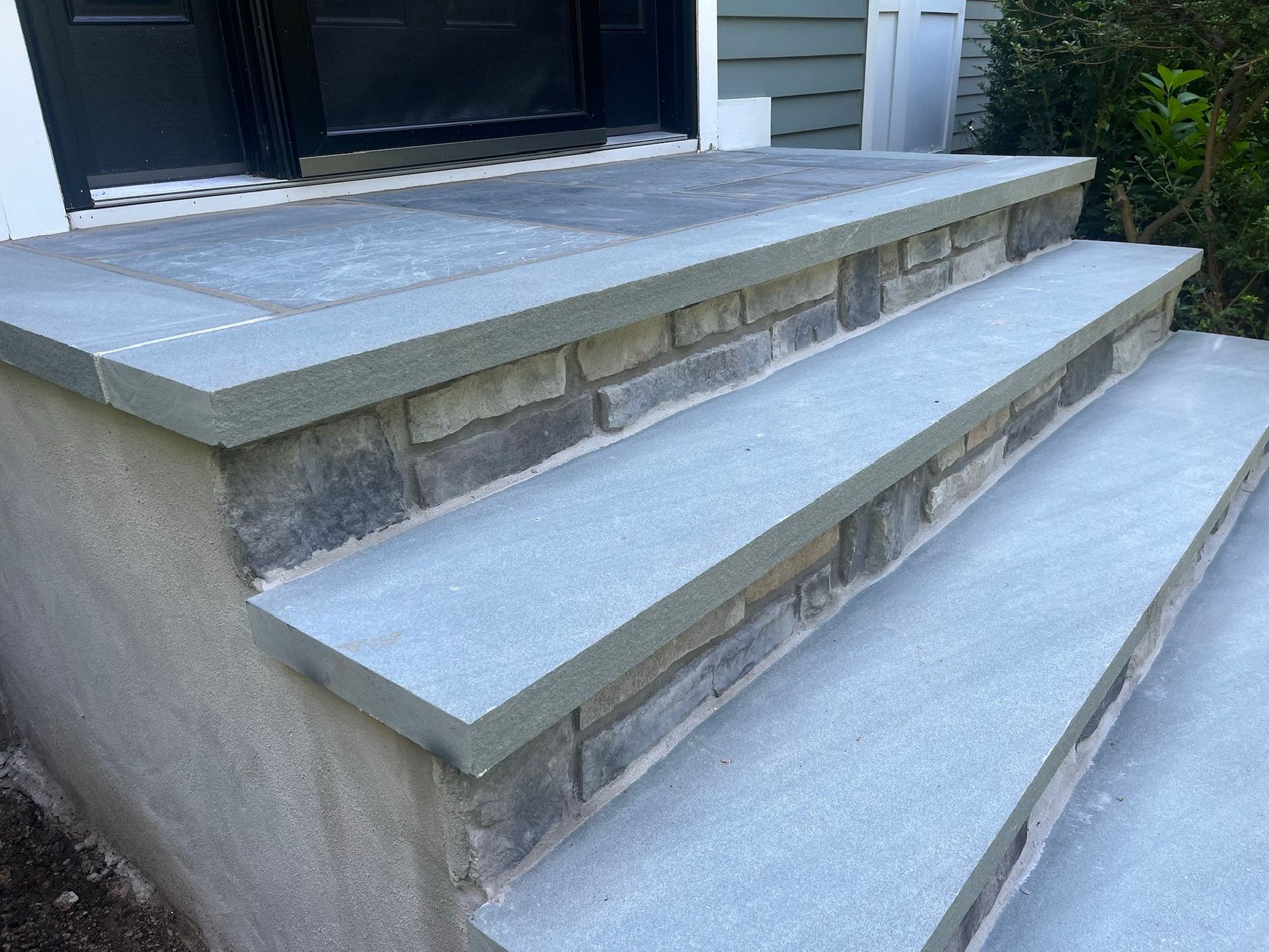Concrete front steps with gray stone treads leading to a doorway.