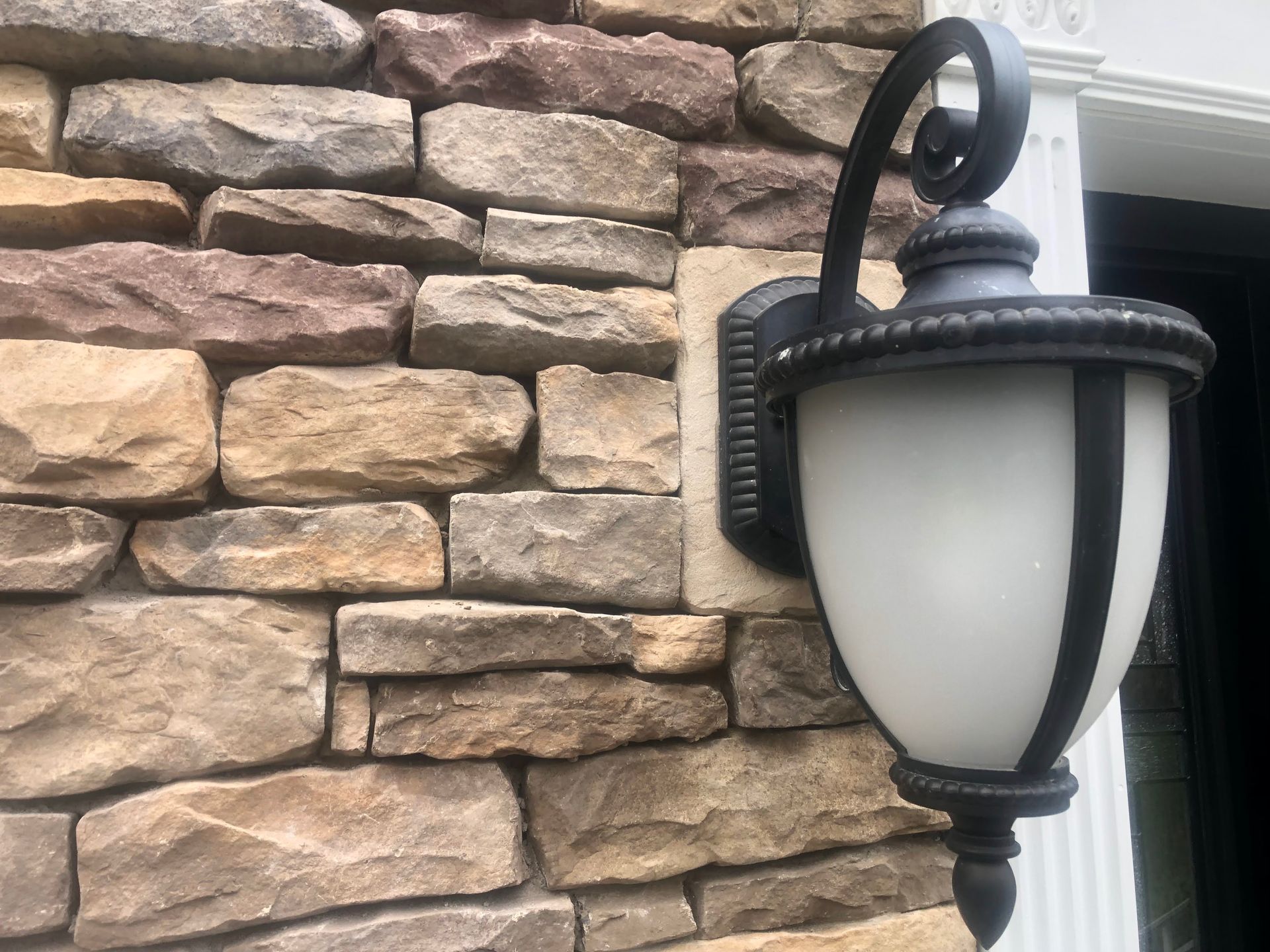 Black wall lantern beside a doorway on a stone exterior wall