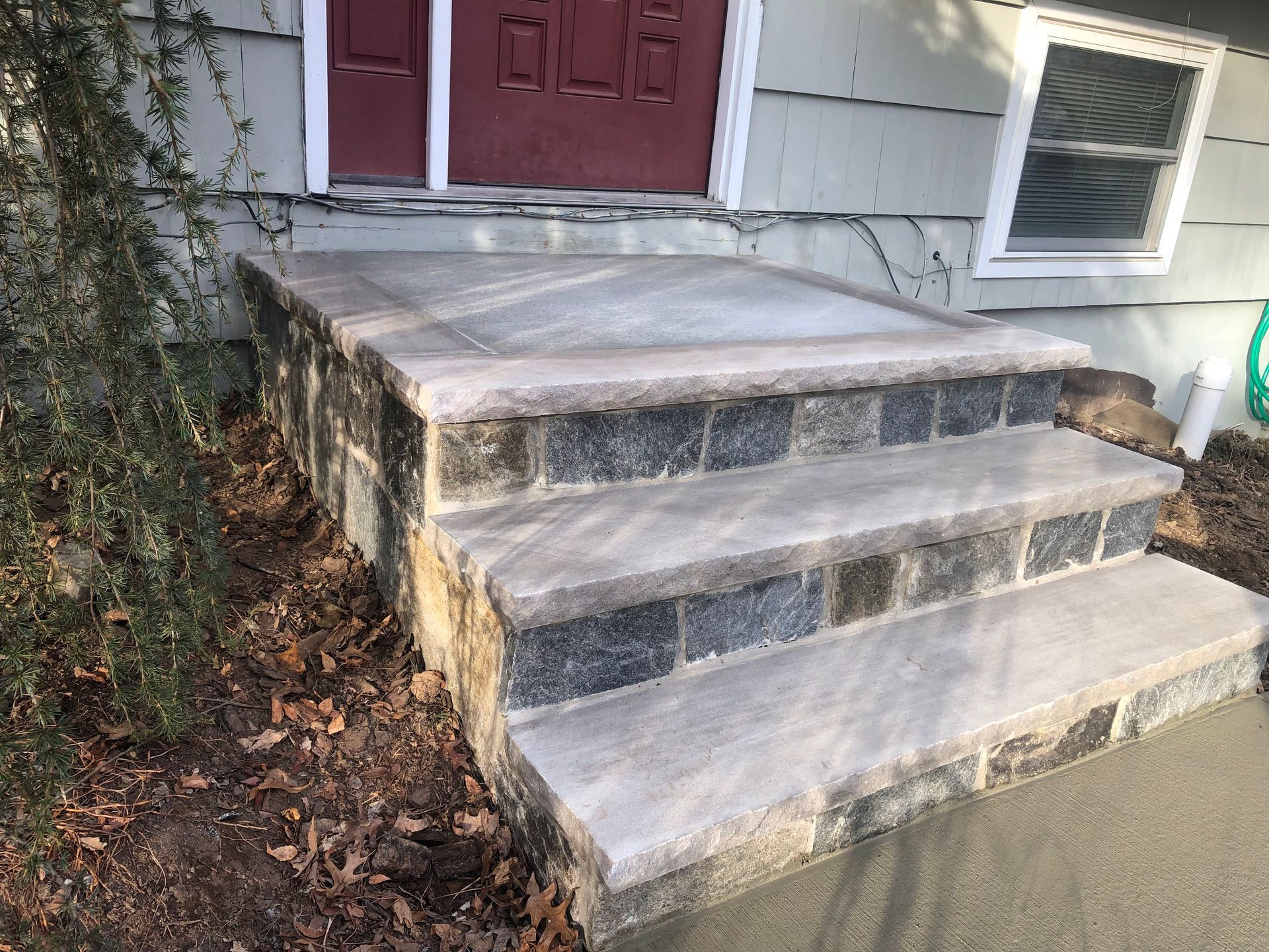 Concrete front steps leading to a red door on a house exterior