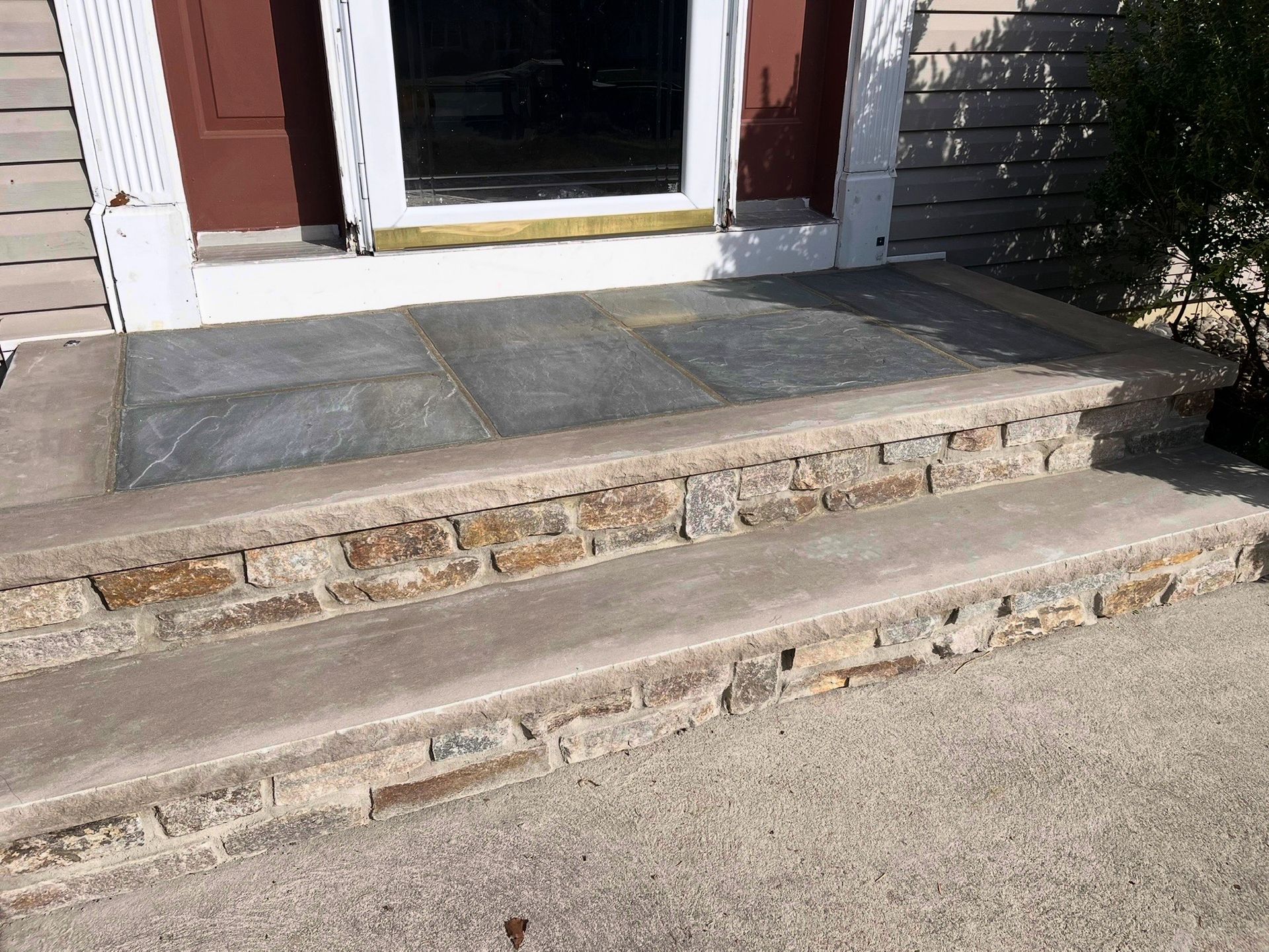 Stone front steps leading to a doorway with chipped concrete and a worn threshold