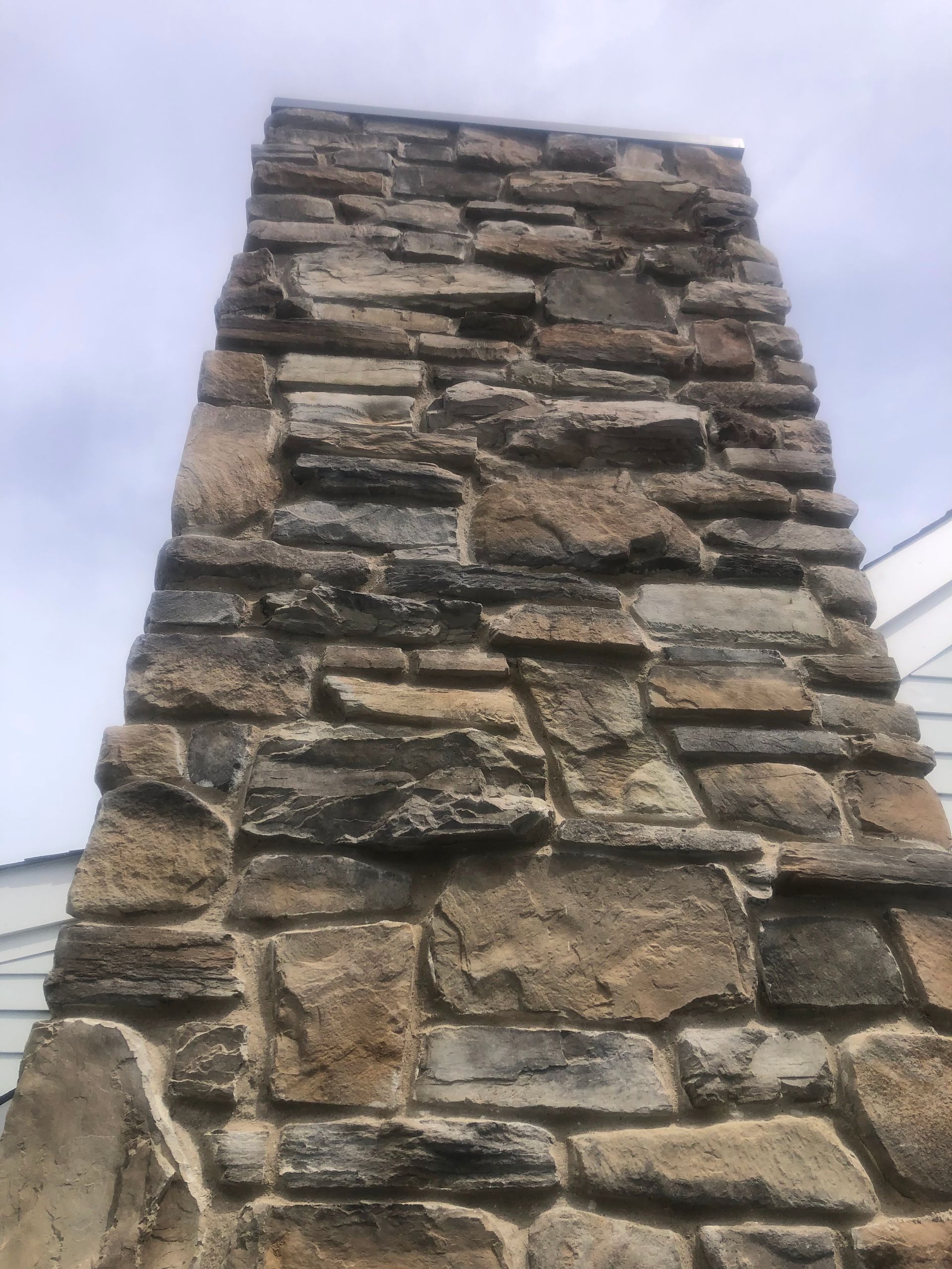 Stone chimney rising against a pale cloudy sky