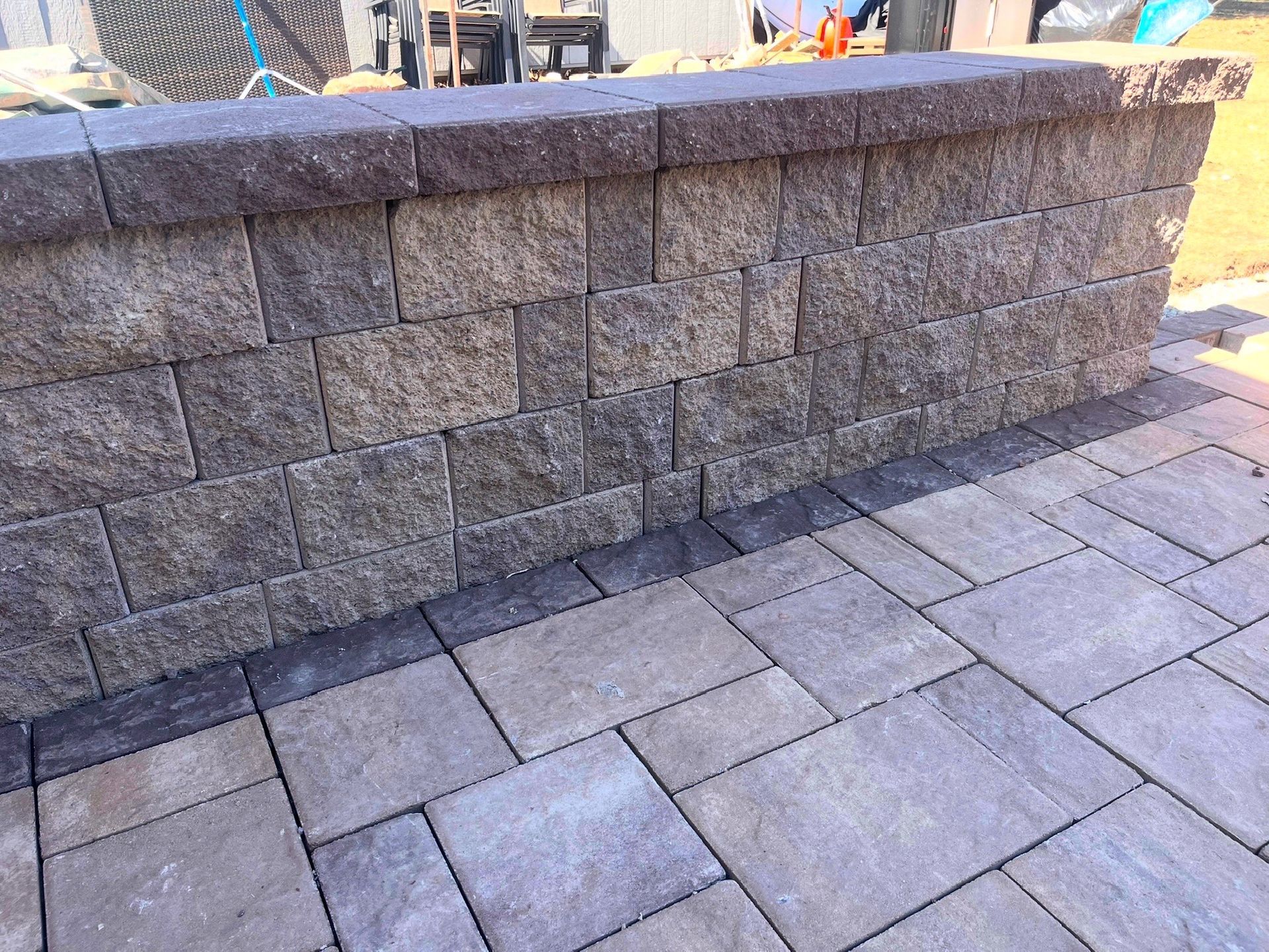 Stone retaining wall beside a paved walkway in an outdoor setting