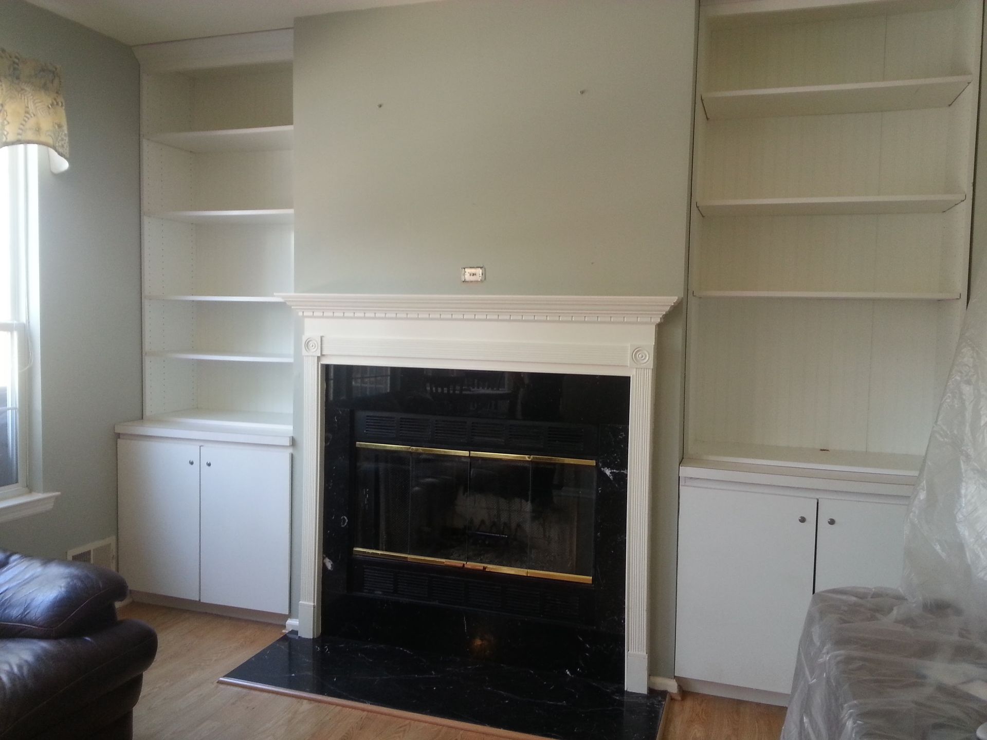 Living room with white built-in shelves flanking a fireplace and window seat, black fireplace surround.