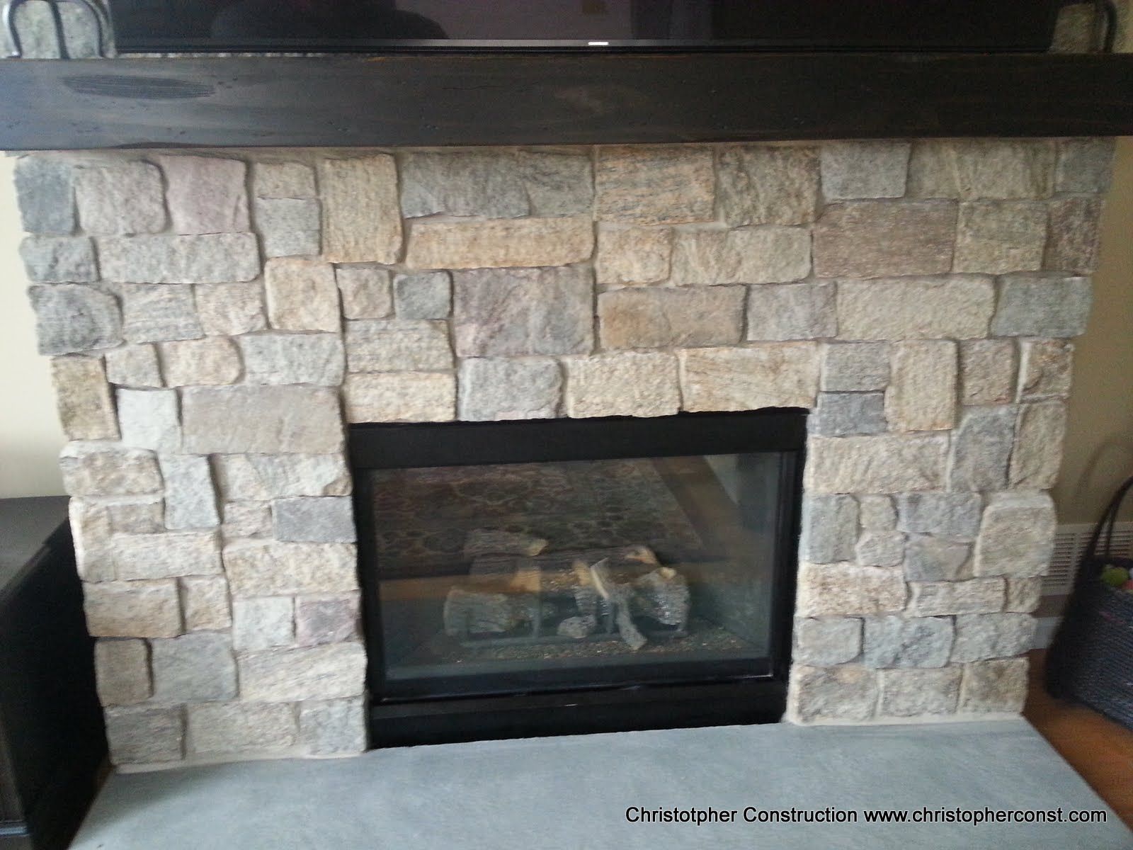 Stone fireplace with a dark mantel and glass-front insert in a living room