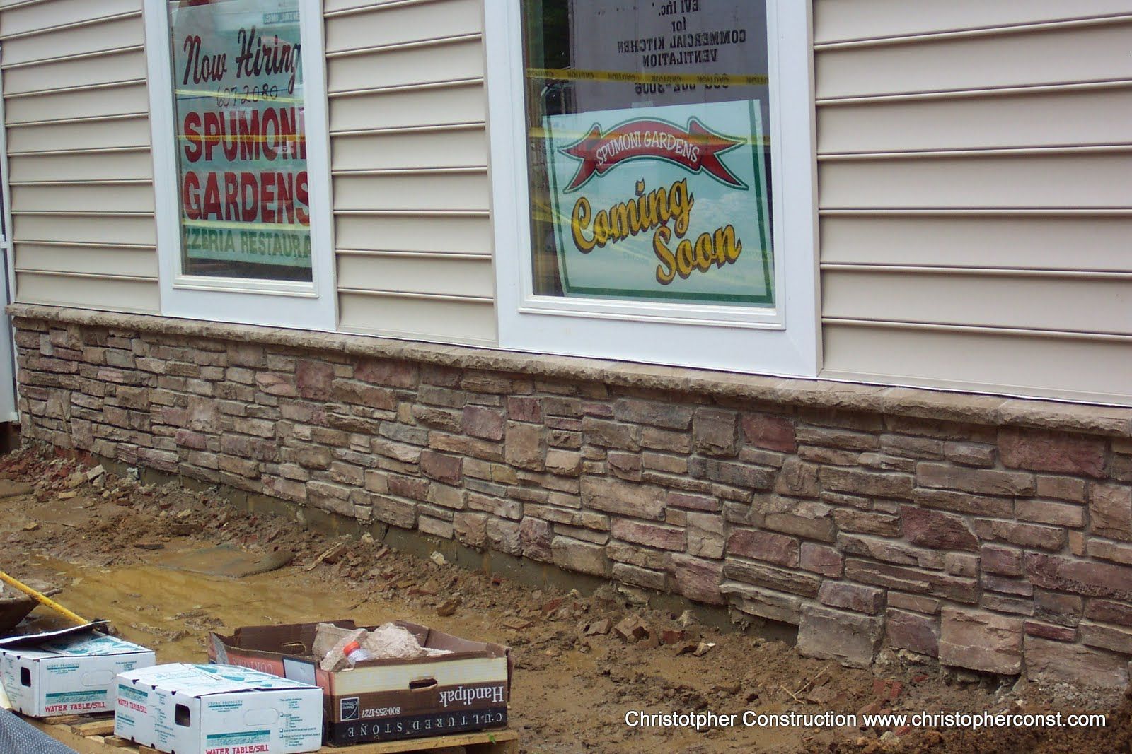 Storefront windows advertising Spring Garden and Country Store above a stone wall
