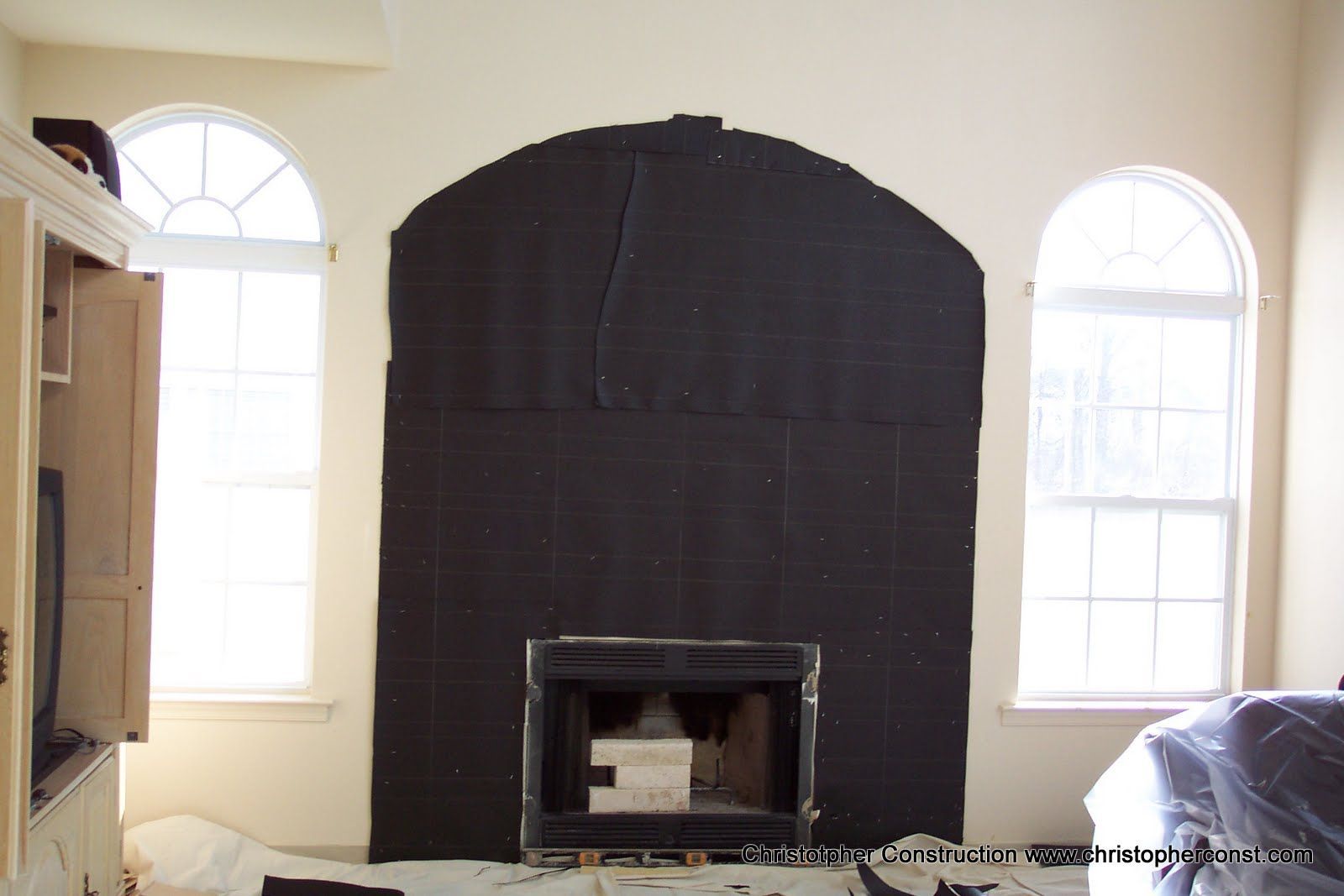 Living room with a large black-painted fireplace wall between two arched windows