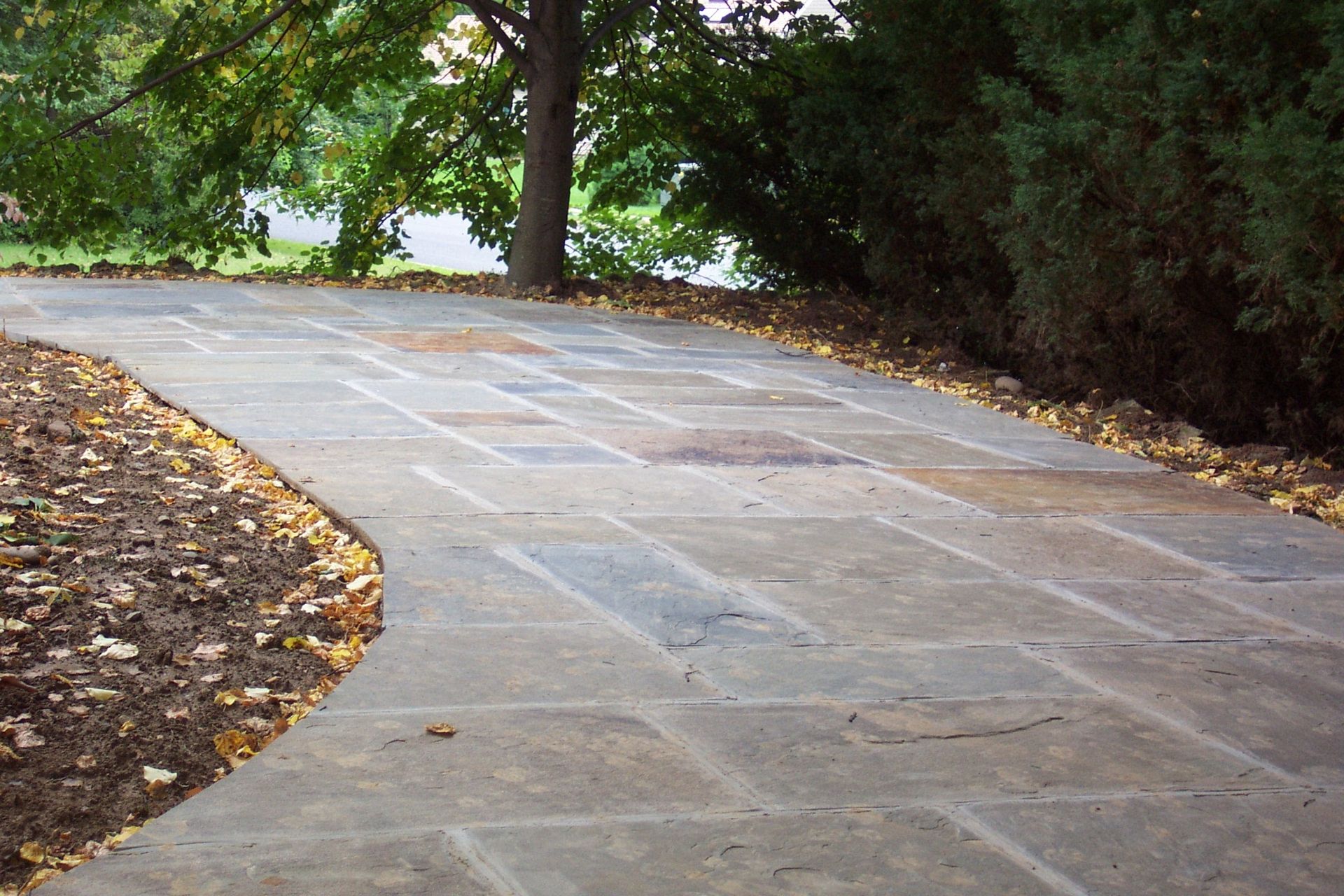 Curved stone walkway bordered by mulch and trees in a park-like setting