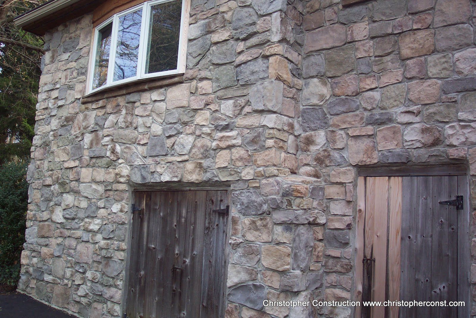Stone building facade with two wooden doors and a small window above one door