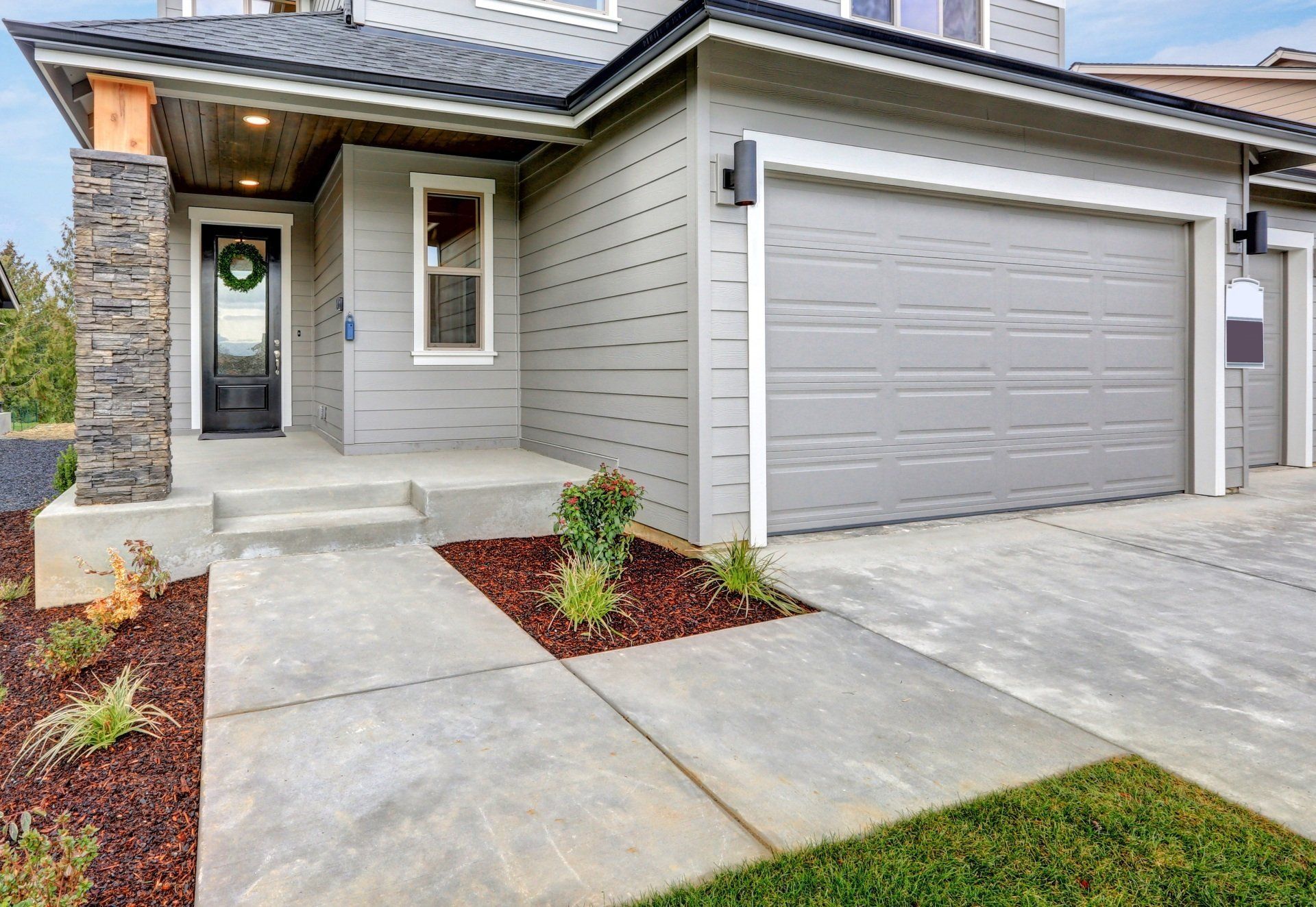 Modern suburban house exterior with gray siding, front porch, and a two-car garage.