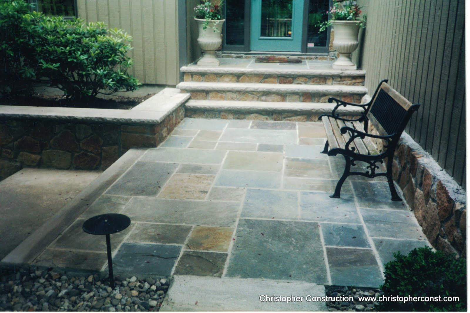 Stone patio courtyard with steps, a bench, and a doorway at the end