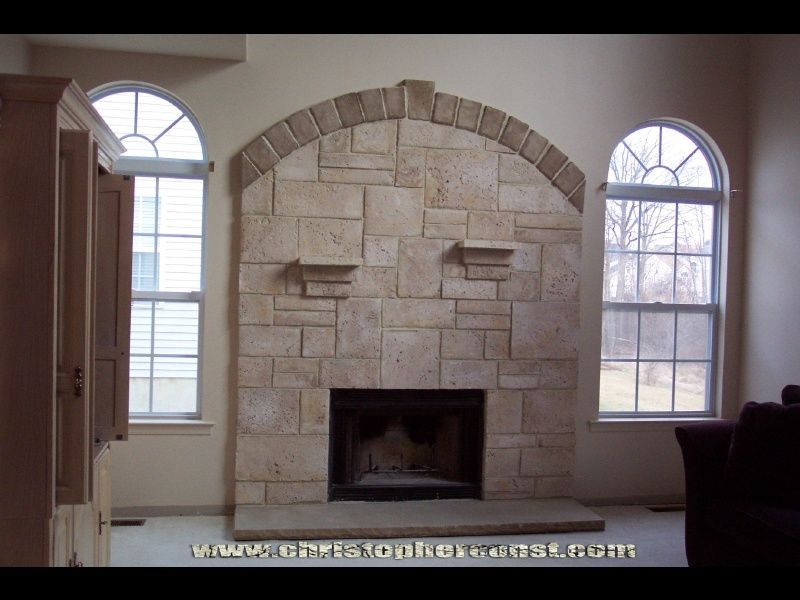 Stone fireplace with arched mantel between two windows in a living room