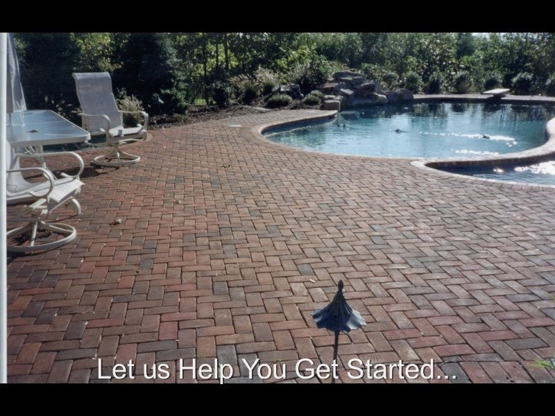 Brick patio beside a blue swimming pool with lounge chairs and trees in the background