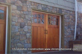 Stone house exterior with wooden double doors and glass panels, with “Christopher Construction” watermark.