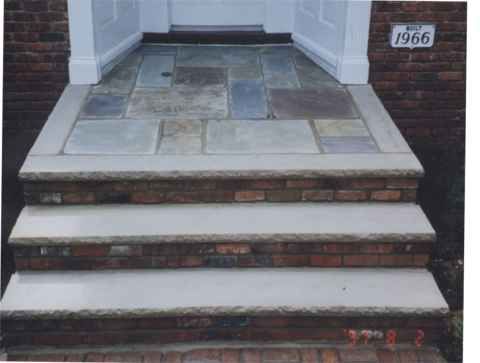 Three concrete front steps leading to a doorway, with a small “1966” plaque on the right wall.