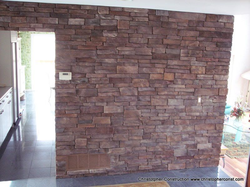 Interior wall with brown stacked-stone veneer beside a doorway and tiled floor