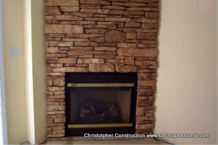Stone fireplace with a black mantel in a beige living room wall.