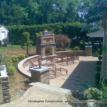 Backyard patio with brick outdoor fireplace, curved seating area, and garden landscaping