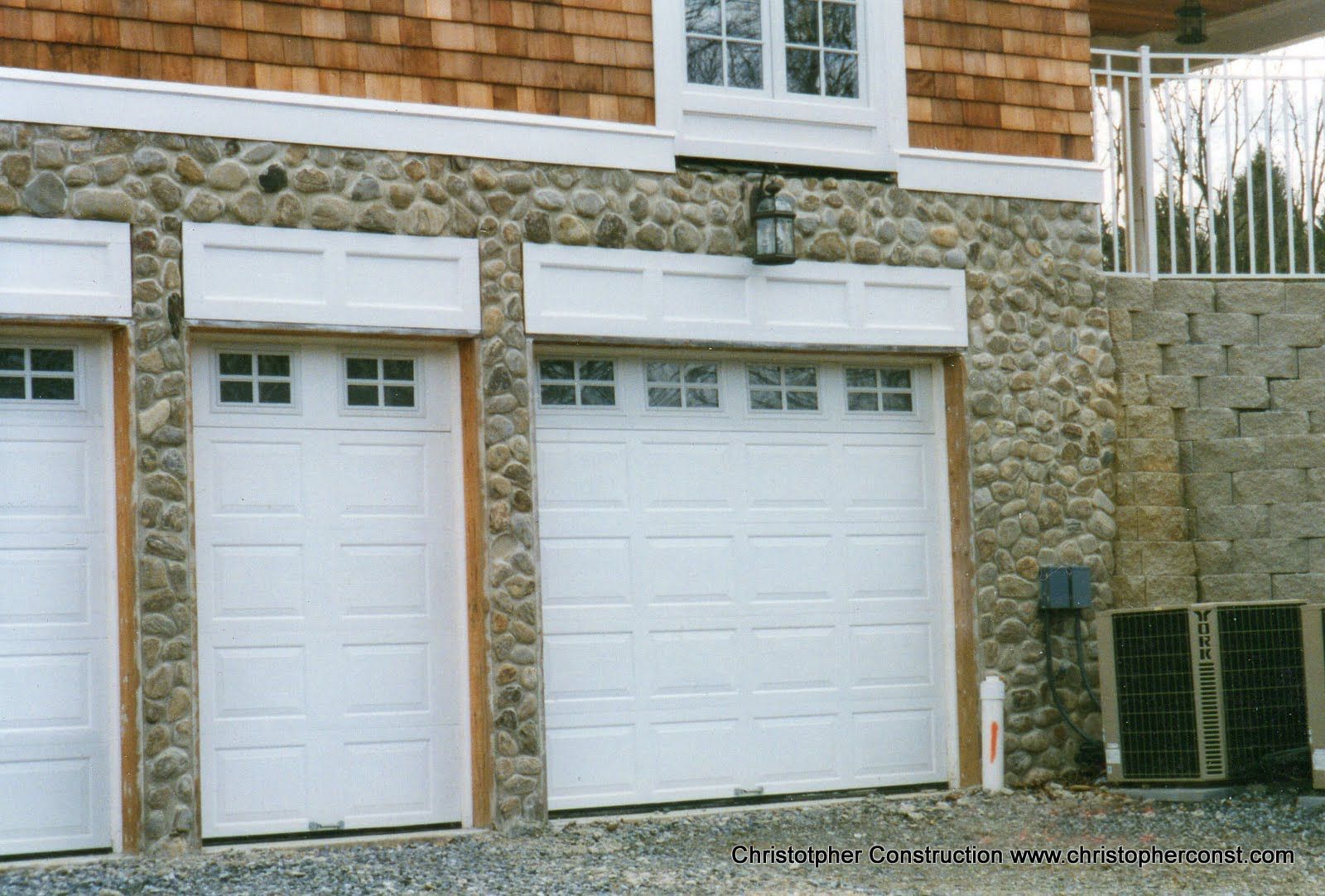 White garage and side door set in a stone and shingle house exterior.
