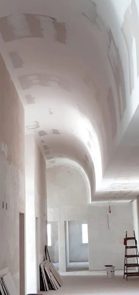 Interior blanco luminoso con techo abovedado, una puerta y una escalera de mano a la derecha