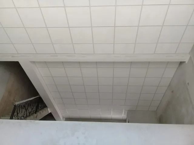Vista de un rellano de escalera con paredes y techo revestidos de azulejos blancos, visto desde arriba