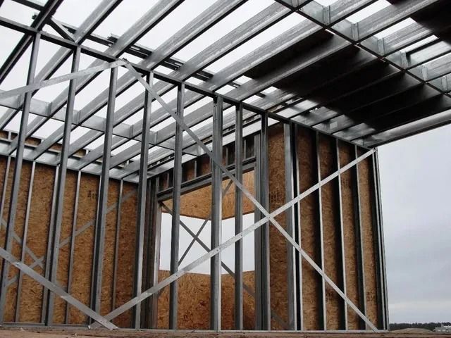 Edificio con estructura de acero en construcción, con revestimiento de madera y un techo metálico parcialmente instalado