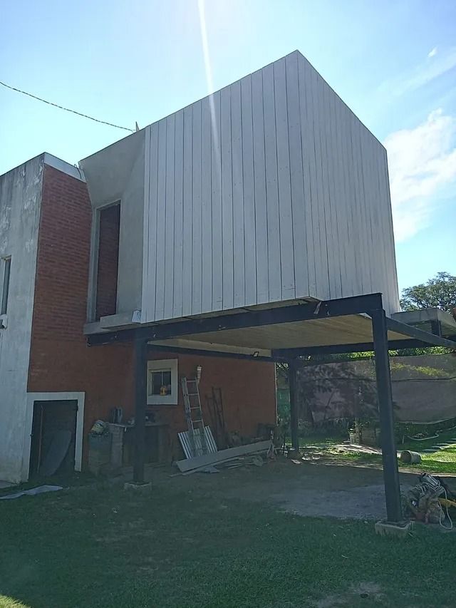 Casa moderna con un volumen superior blanco, muros inferiores de ladrillo y un garaje abierto en un jardín con césped