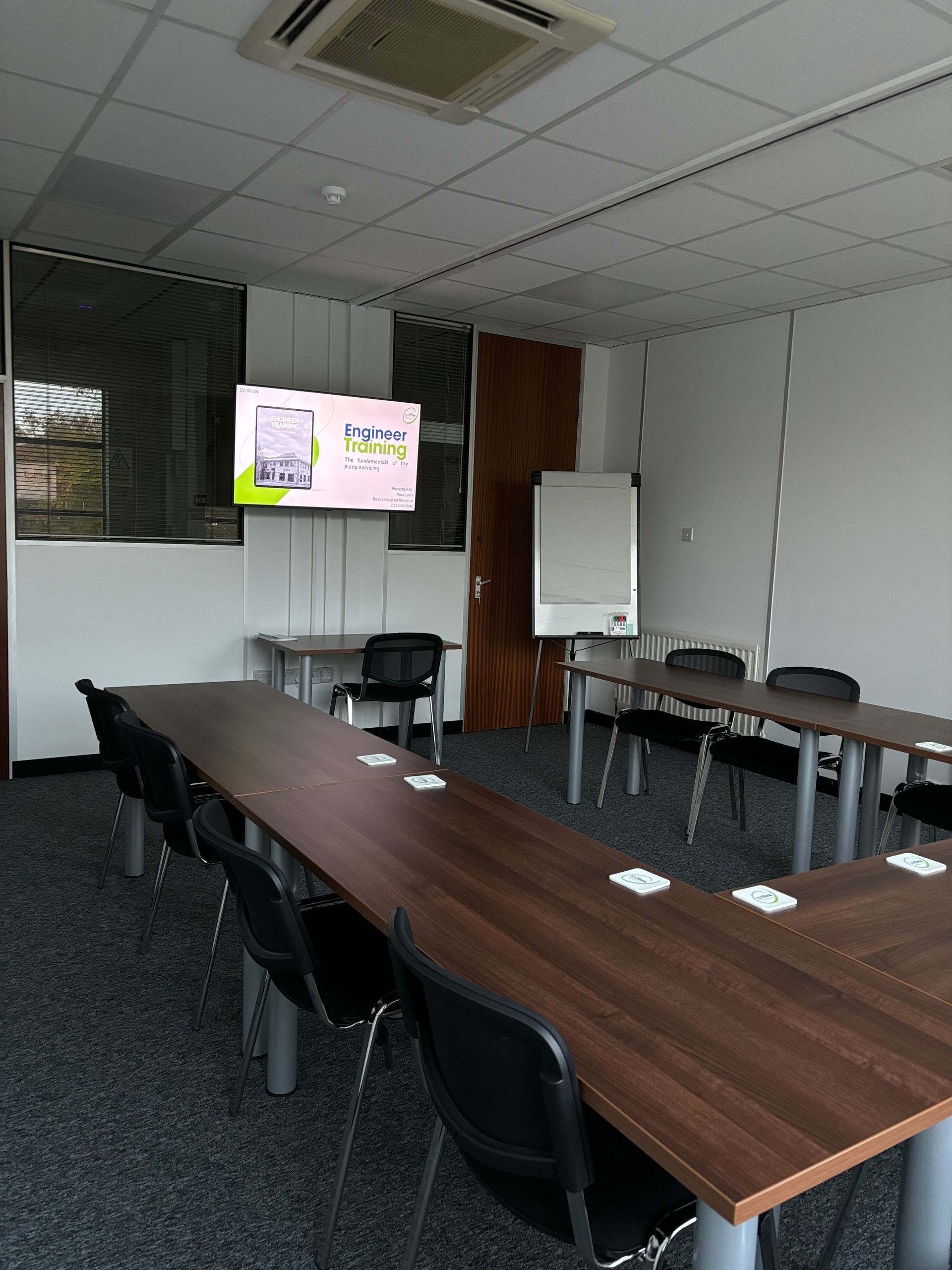 A conference room with tables and chairs and a flat screen tv