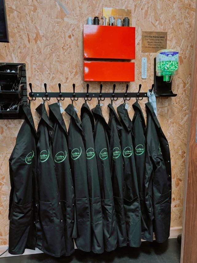 A bunch of coats are hanging on a rack in a room.