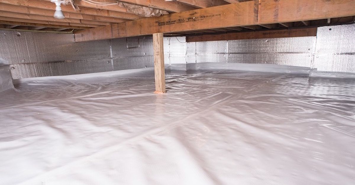 An interior view of a wooden attic frame with foam insulation between beams and a square skylight open to the sky.
