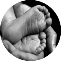 Tiny baby feet resting in a person's hand, black and white.