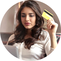 Woman holding a credit card, looking at a laptop, possibly shopping online.