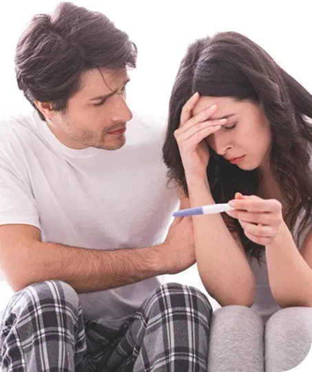A woman holds a pregnancy test, looking distraught while a man comforts her.