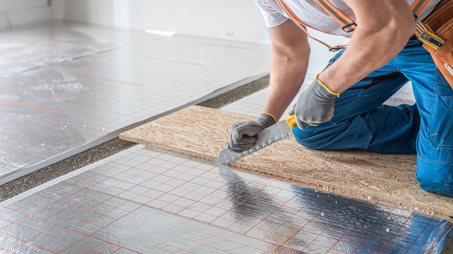 Insulation installer fitting underfloor batts between timber floor joists in a subfloor