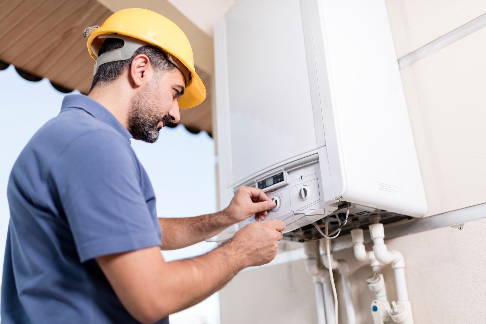 Technician with a yellow safety helmet installing a residential boiler