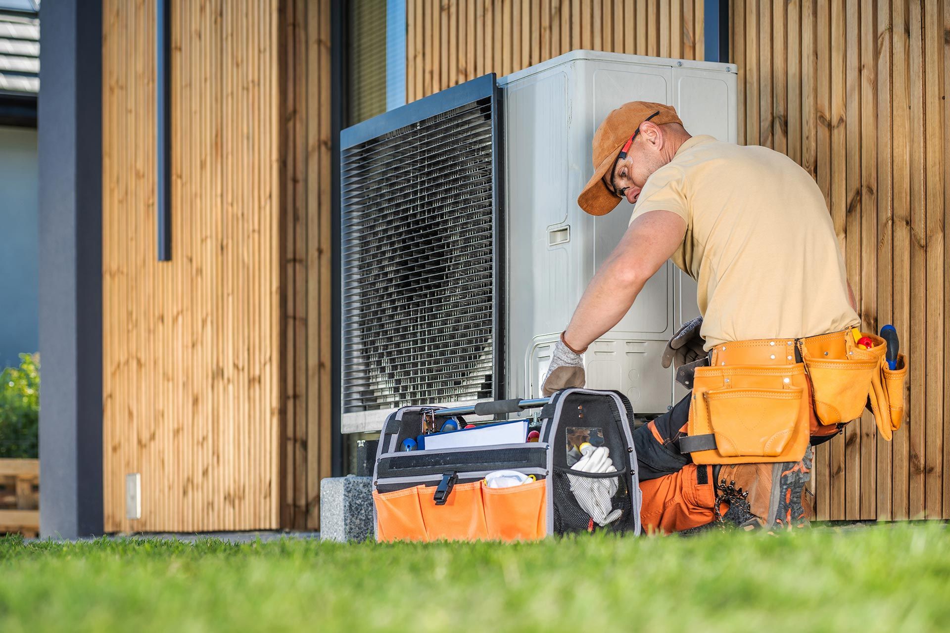 HVAC technician servicing an outdoor heat pump unit at a modern Tauranga home. HVAC technician servicing an outdoor heat pump unit at a modern Tauranga home.