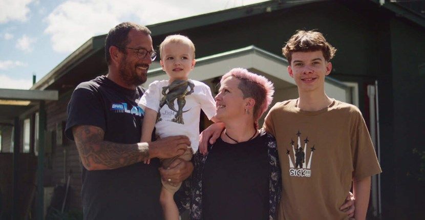 A family is posing for a picture in front of their house.