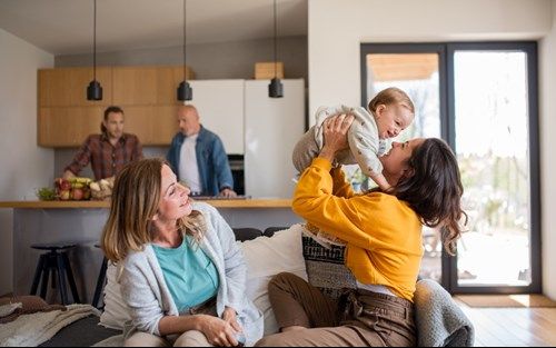 A woman is holding a baby in her arms while sitting on a couch.