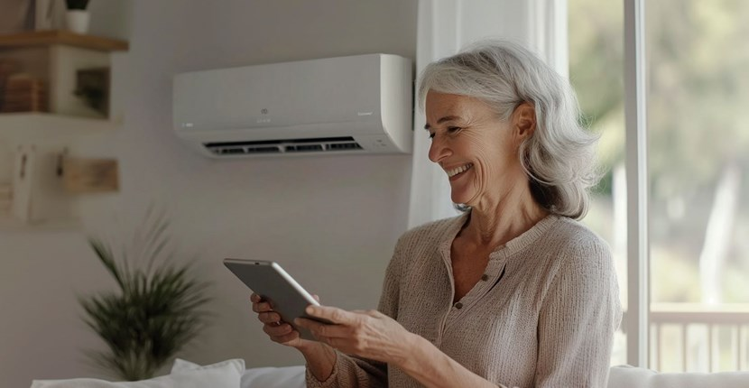 An elderly woman is using a tablet computer in a living room.