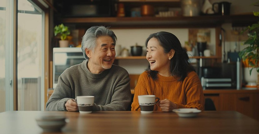 A man and a woman are sitting at a table with cups of coffee.